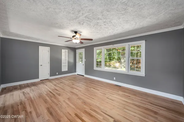 a view of an empty room with wooden floor and a window