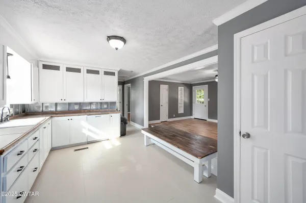 a large white kitchen with kitchen island a sink stainless steel appliances and cabinets