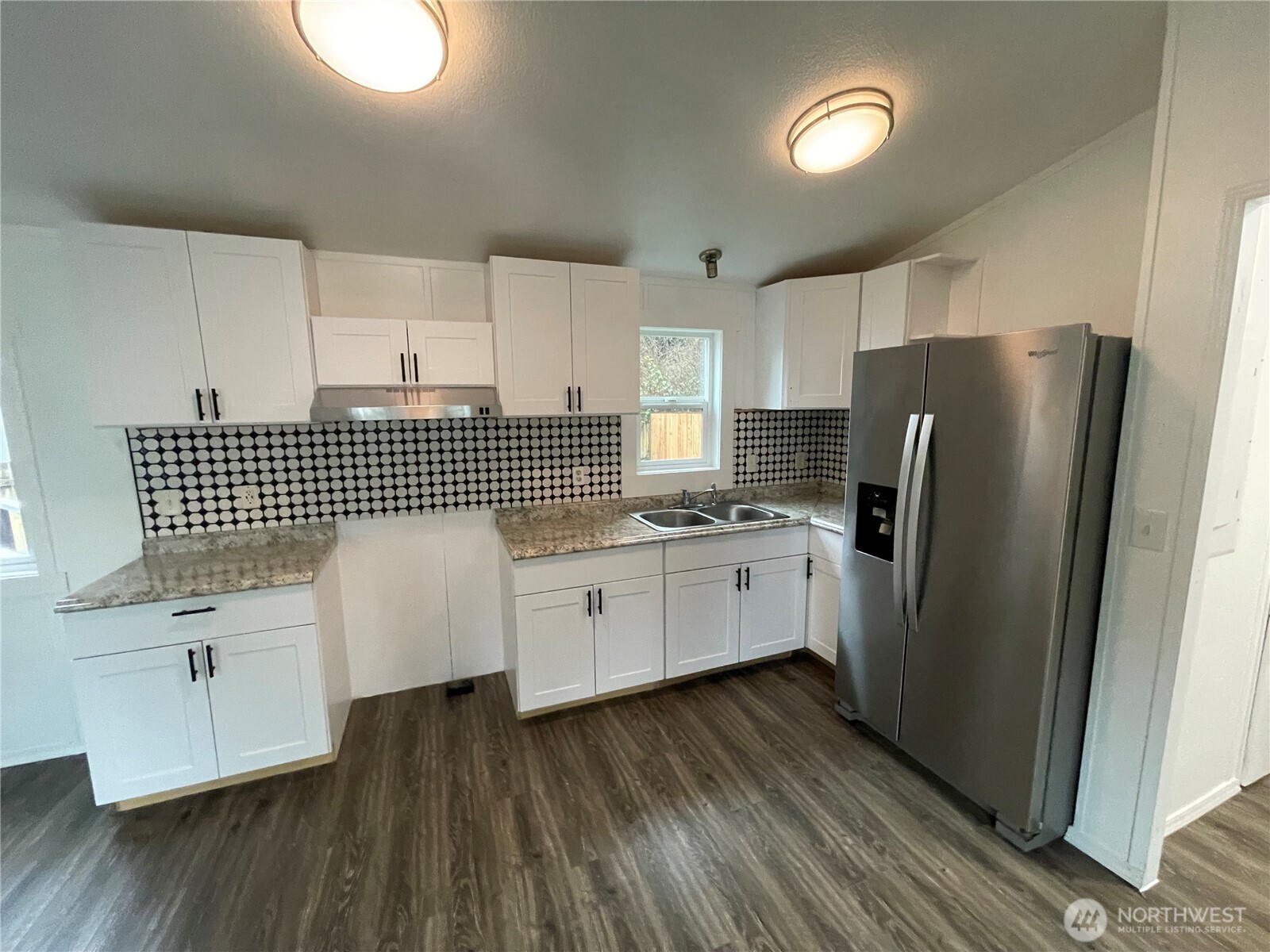 5705 Littlerock Road Southwest, Unit 16 Tumwater, WA 98512 - Photo 5 of 18 a kitchen with granite countertop white cabinets a refrigerator a sink and dishwasher with wooden floor