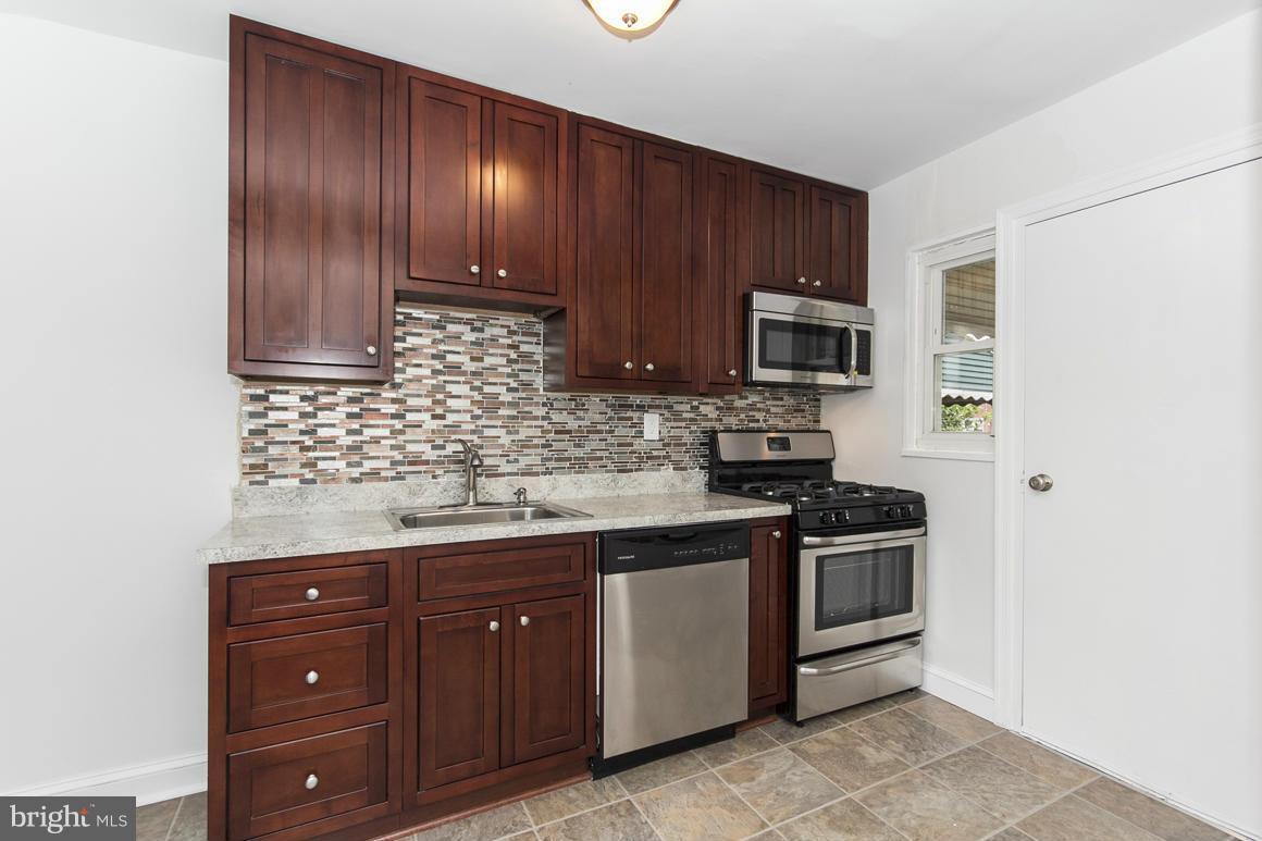 1902 Jasmine Road Baltimore, MD 21222 - Photo 5 of 27 a kitchen with stainless steel appliances granite countertop wooden cabinets and a stove top oven