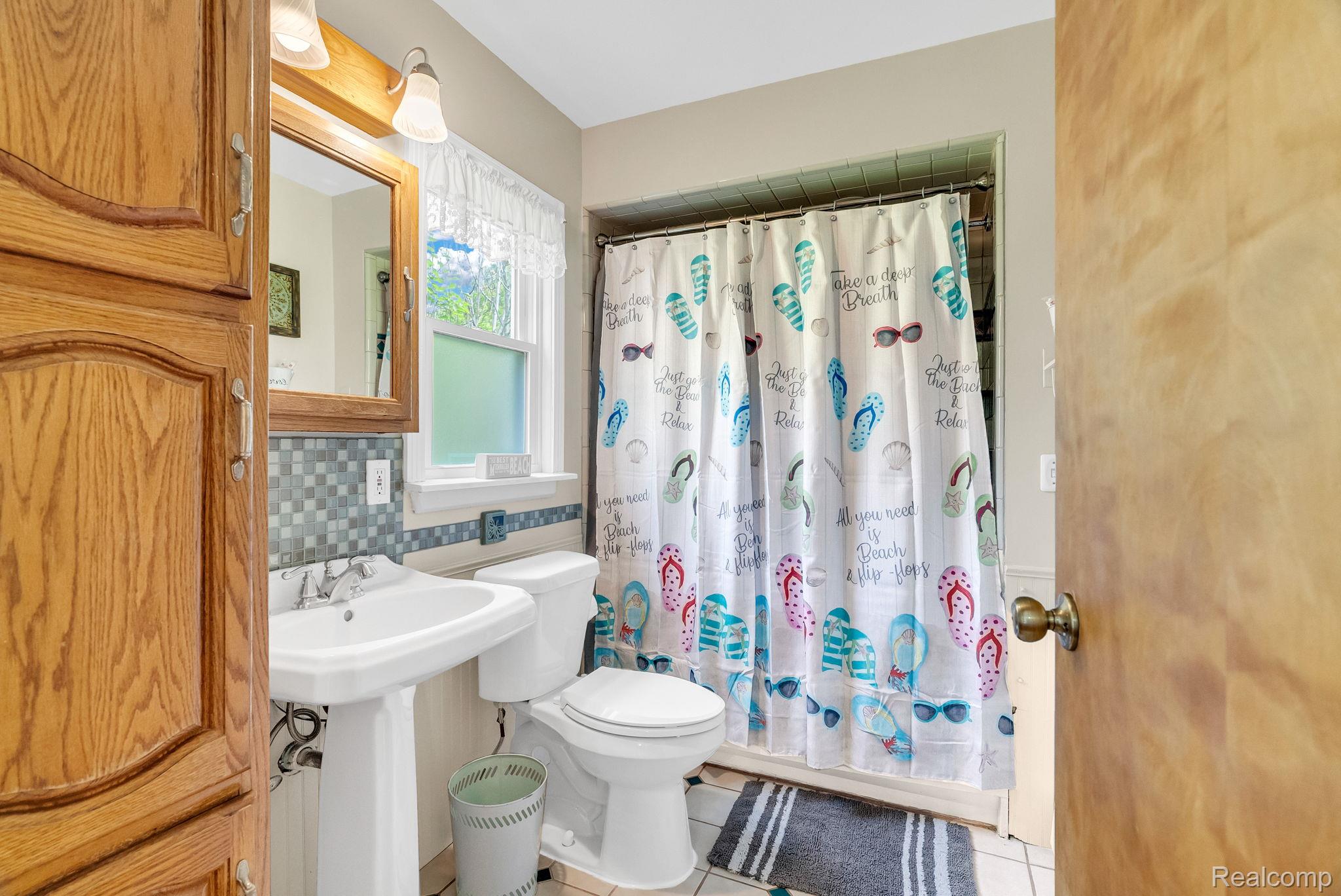 7489 Aspen Road Lexington, MI 48450 - Photo 37 of 62 Bathroom featuring a pedestal sink, white toilet, and a window with a valance