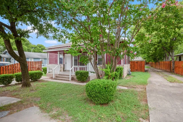 a front view of a house with a yard and a large tree