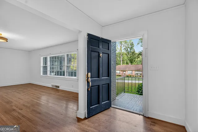 a view of an empty room with wooden floor and a window