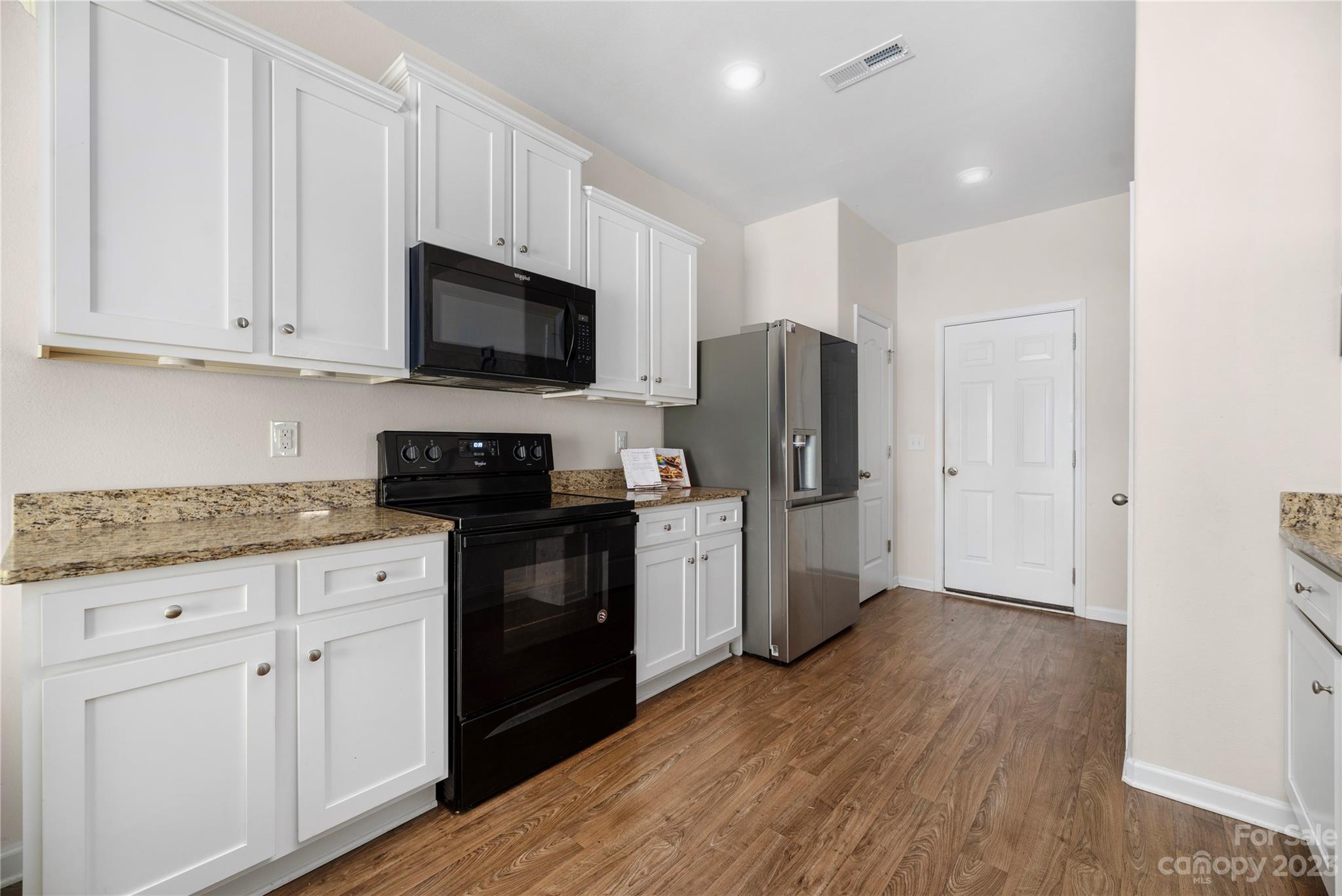 6415 Jerimoth Charlotte, NC 28215 - Photo 8 of 22 a kitchen with stainless steel appliances granite countertop a refrigerator stove a sink and white cabinets with wooden floor