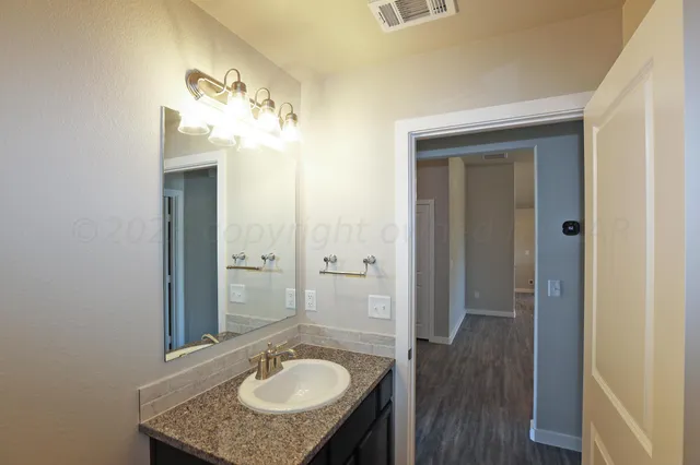 a bathroom with a granite countertop sink a mirror and a shower