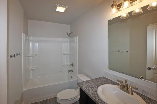 a bathroom with a granite countertop sink toilet and shower