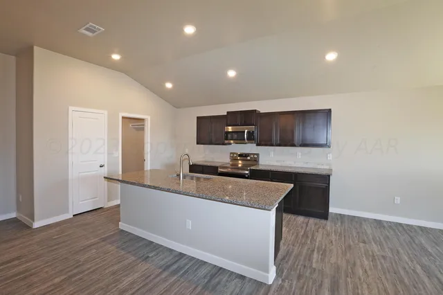 a white kitchen with wooden floor and stainless steel appliances