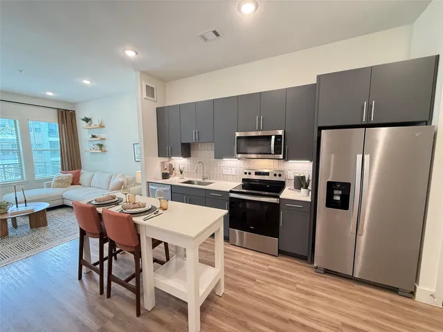 a kitchen with stainless steel appliances a dining table chairs stove refrigerator and microwave