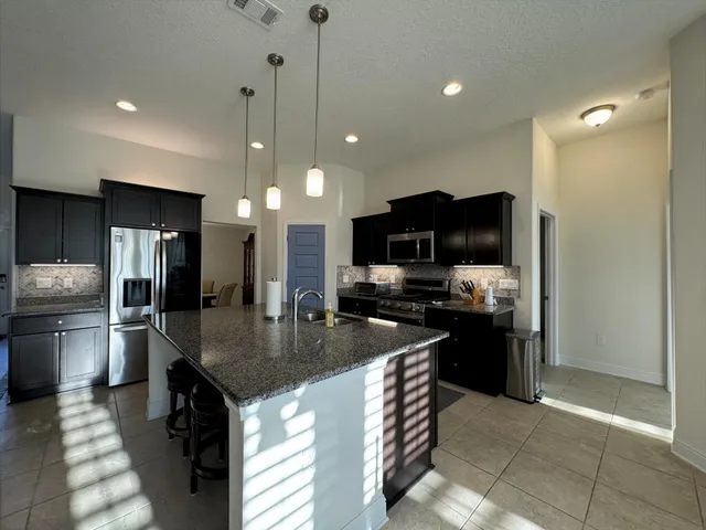 a kitchen with stainless steel appliances granite countertop a sink a stove and a refrigerator
