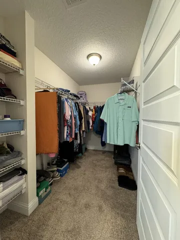 a view of walk in closet with clothes and shoes