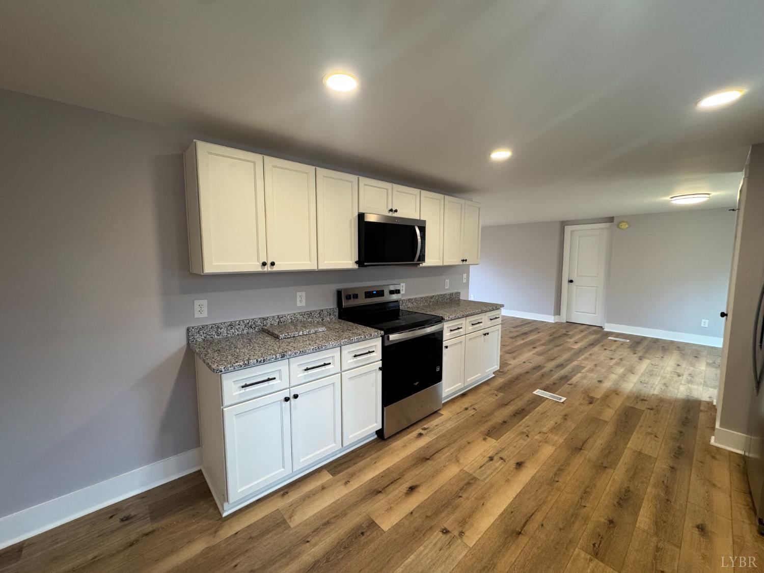 137 Ridgeview Lane Madison Heights, VA 24572 - Photo 6 of 22 a kitchen with granite countertop a stove top oven a sink dishwasher and a microwave with wooden floor