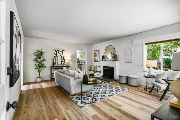 a living room with furniture a rug a fireplace and a large window