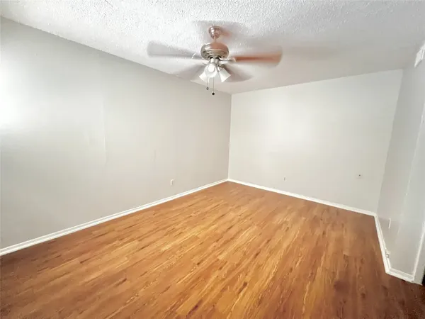 a view of a room with wooden floor and a ceiling fan