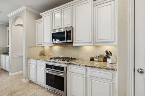 a kitchen with granite countertop white cabinets and stainless steel appliances