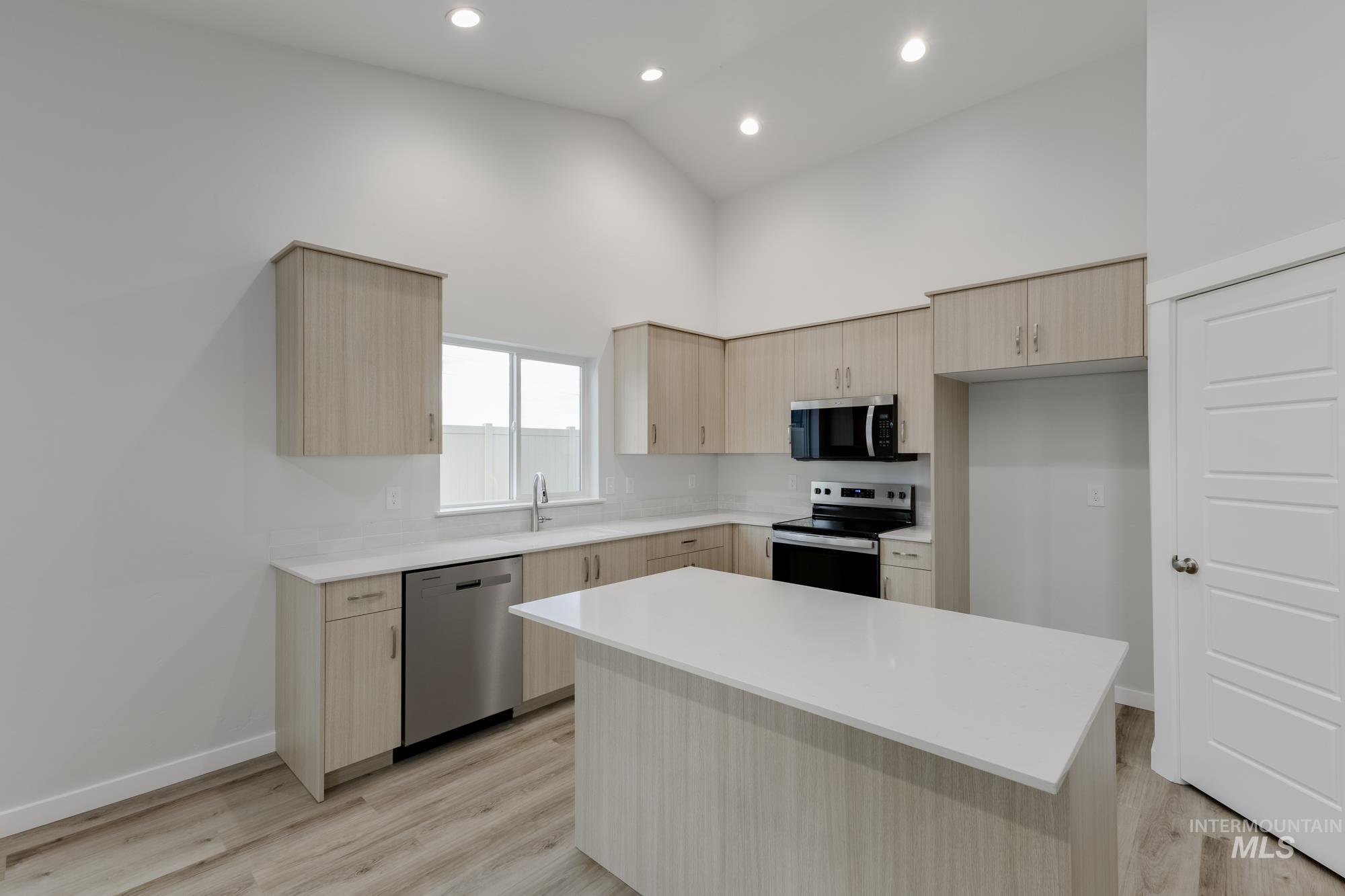 16697 Carlin Avenue Caldwell, ID 83607 - Photo 3 of 18 Kitchen with light brown cabinets, stainless steel appliances, high vaulted ceiling, modern cabinets, and light wood-type flooring