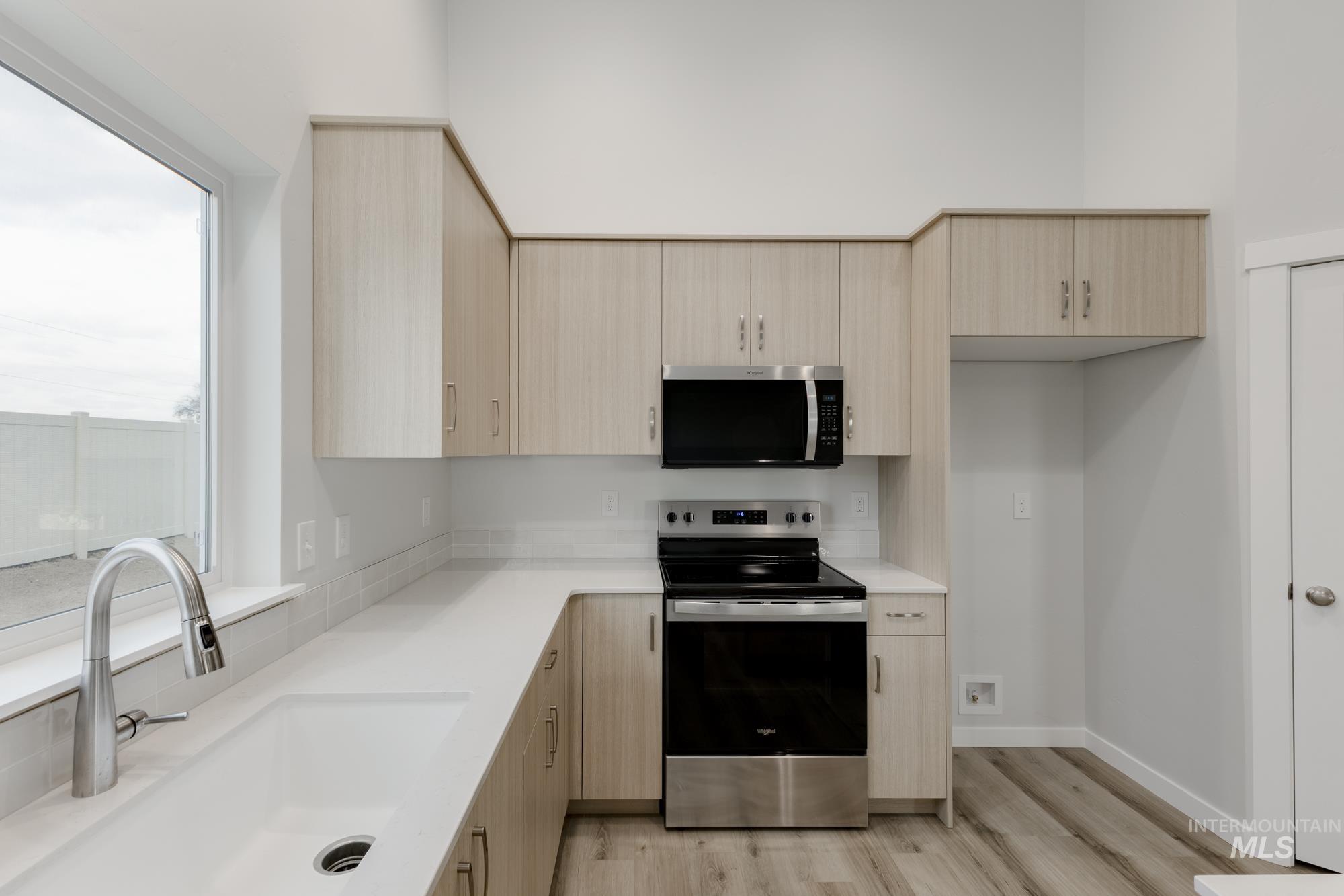 16697 Carlin Avenue Caldwell, ID 83607 - Photo 4 of 18 Kitchen featuring light brown cabinetry, appliances with stainless steel finishes, light wood-type flooring, and modern cabinets