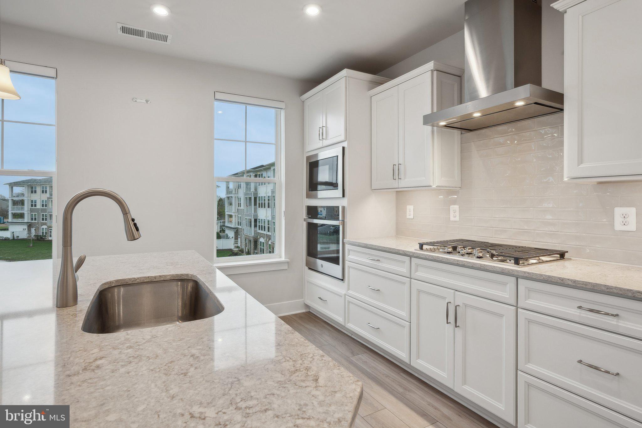 170 Harrier Way, Unit 34 Chester, MD 21619 - Photo 12 of 81 a kitchen with granite countertop a stove a sink and a microwave