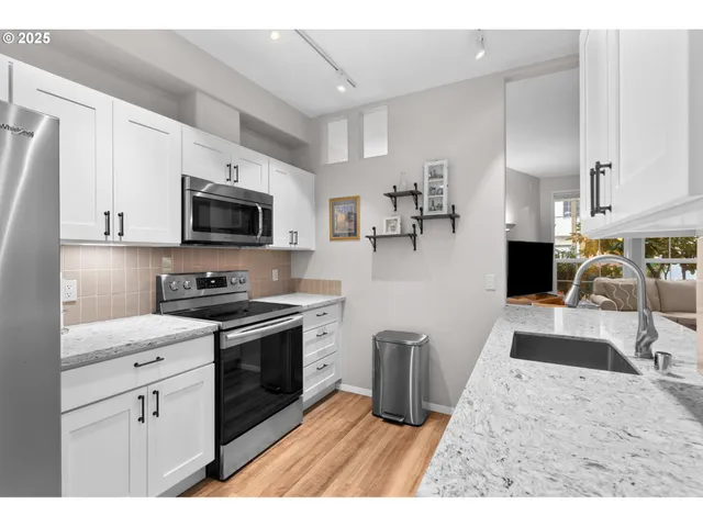 a kitchen with stainless steel appliances granite countertop a sink stove microwave and refrigerator