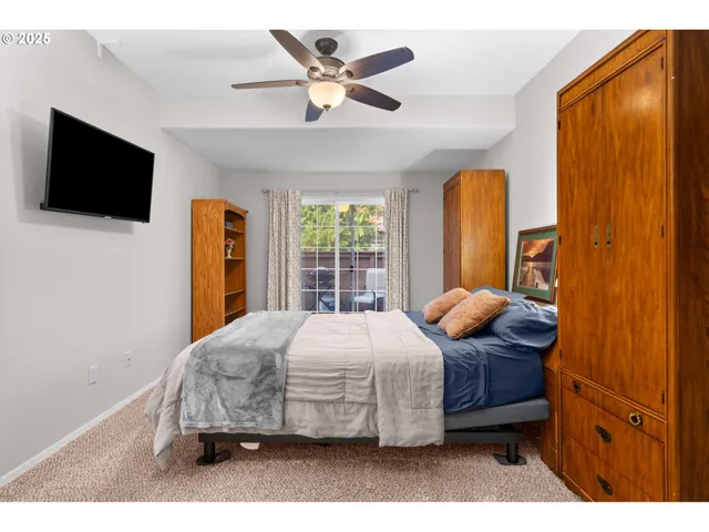 a bedroom with a bed a window and a flat screen tv