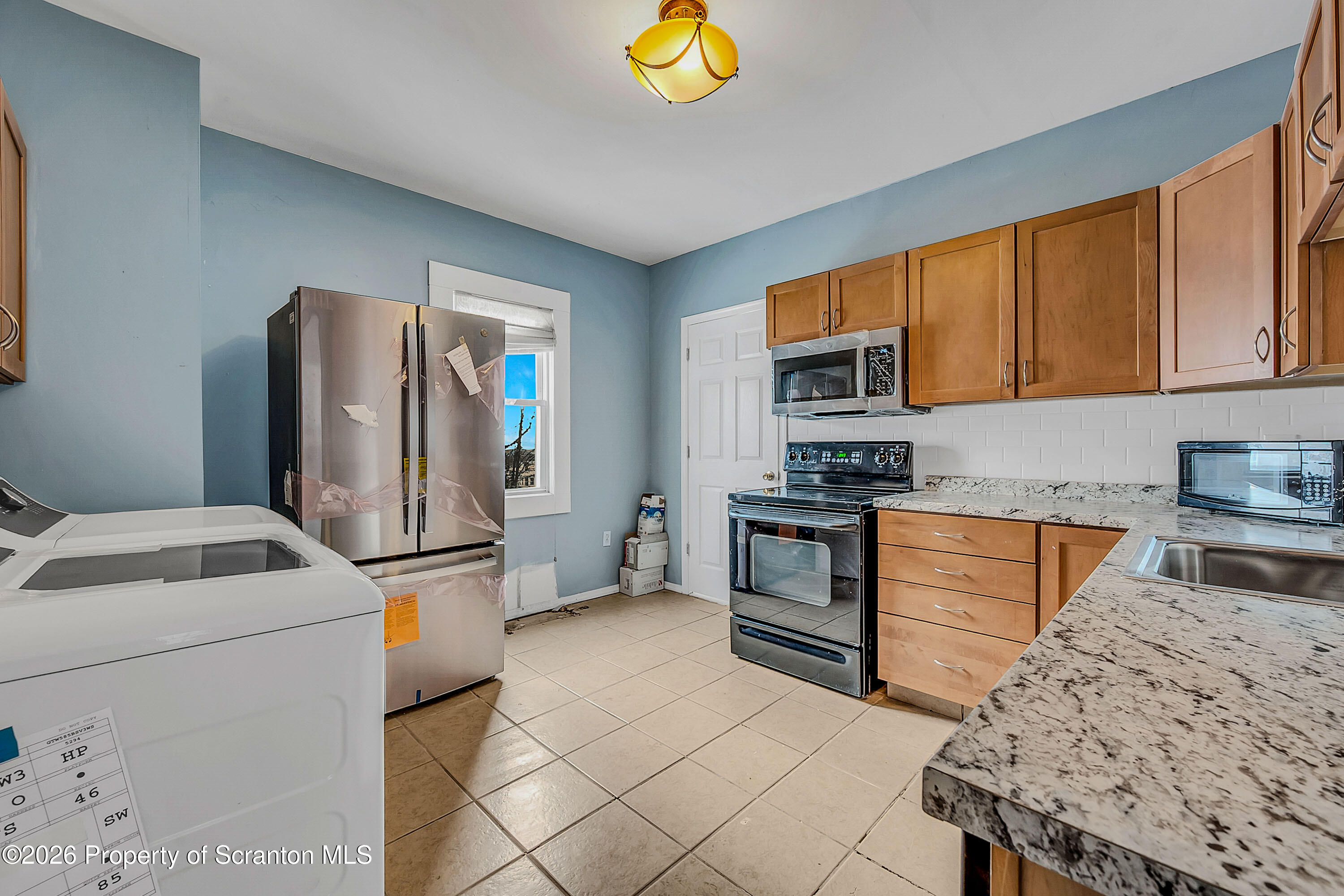 208 East Warren Street, Unit 1 Dunmore, PA 18512 - Photo 18 of 18 a kitchen with stainless steel appliances granite countertop a refrigerator sink stove microwave and cabinets