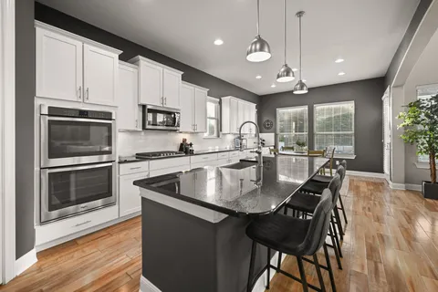 a kitchen with stainless steel appliances granite countertop a stove a sink a microwave a center island and a refrigerator