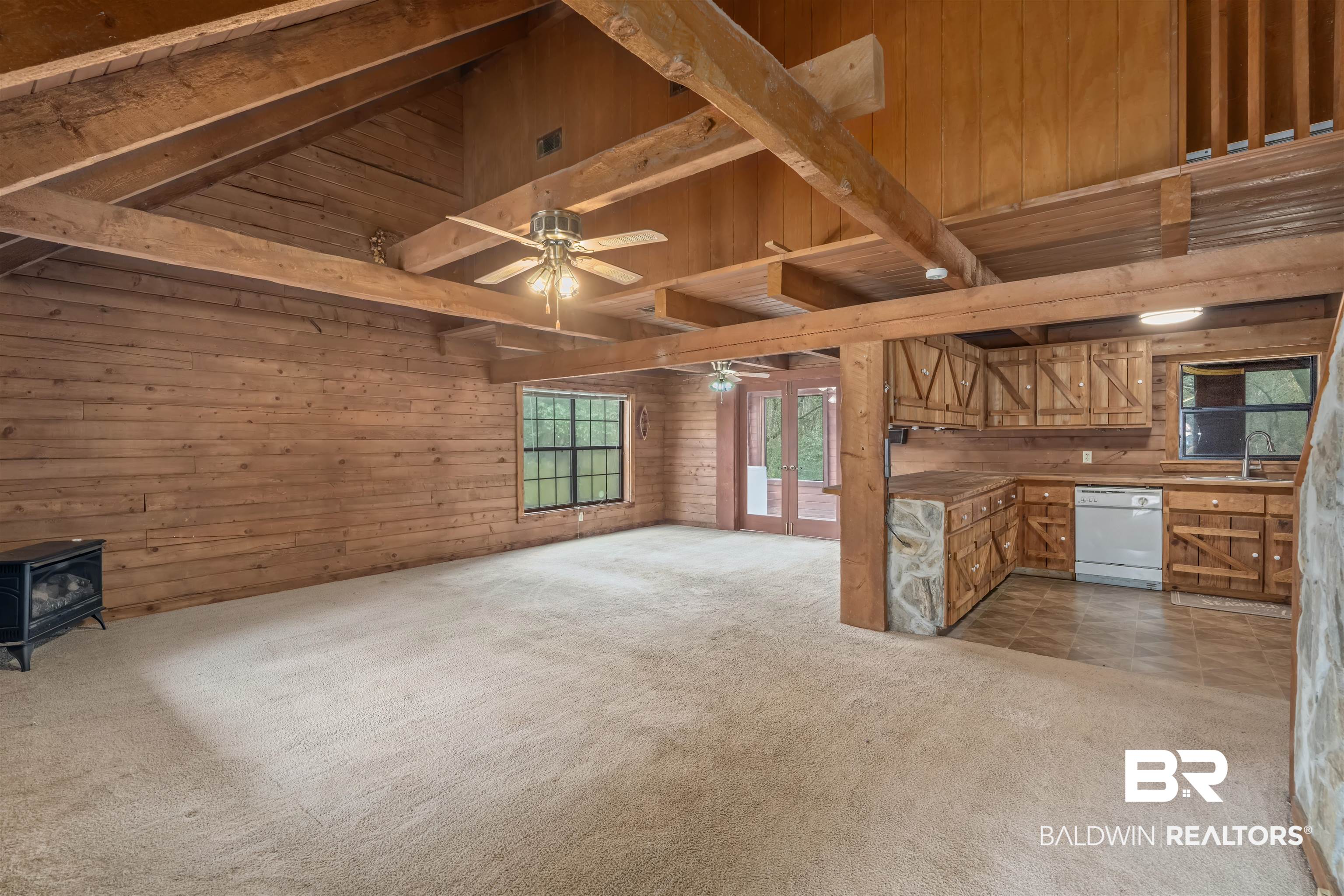 4131 Greaves Road Eight Mile, AL 36613 - Photo 6 of 39 Unfurnished living room featuring beamed ceiling, a wood stove, light colored carpet, and wooden walls