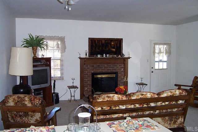 6151 Bushmills Street Raleigh, NC 27613 - Photo 5 of 10 a living room with furniture a fireplace and a flat screen tv