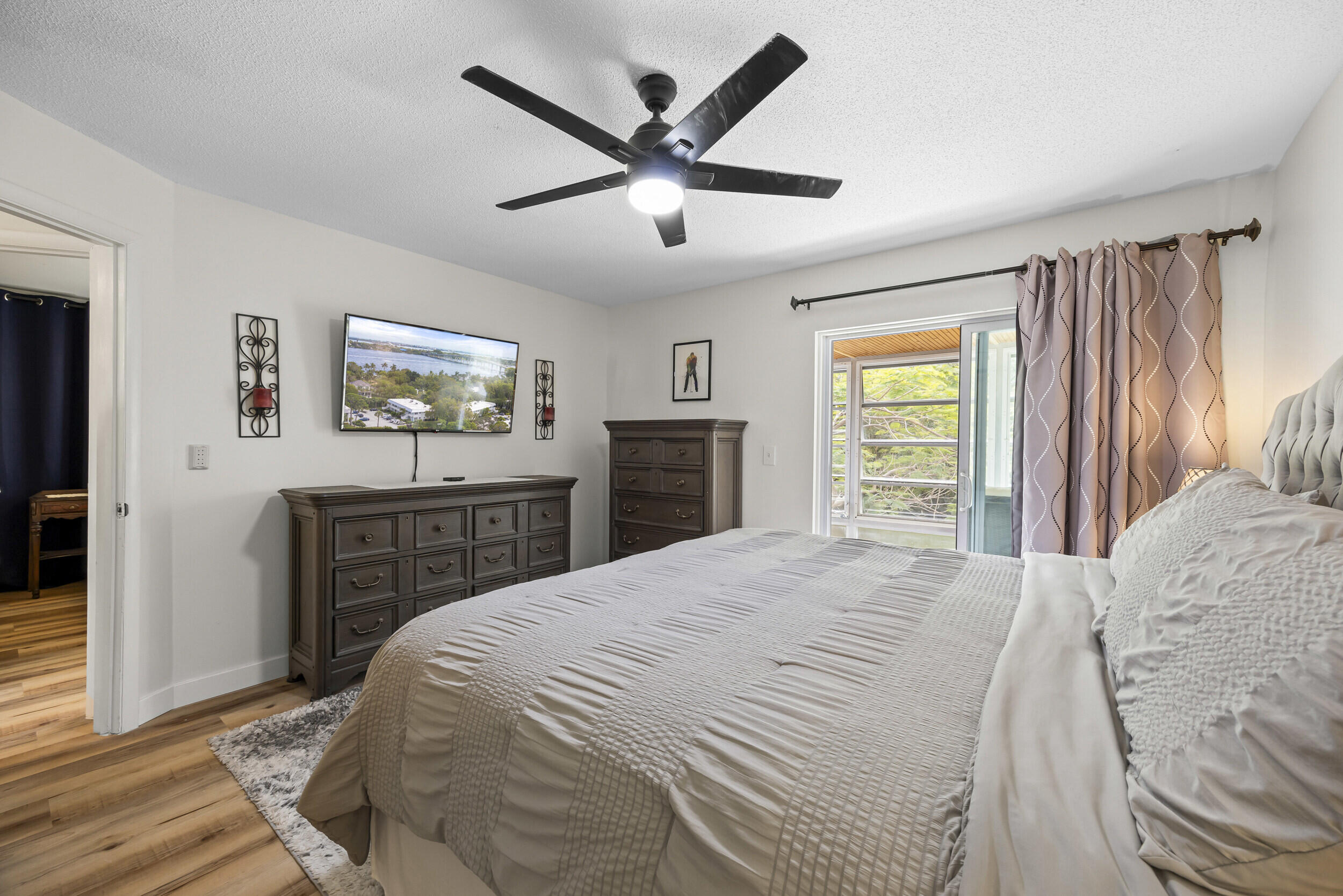 2929 Southeast Ocean Boulevard, Unit 10510 Stuart, FL 34996 - Photo 11 of 37 a bedroom with a bed and dresser with wooden floor