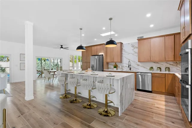 a large kitchen with kitchen island granite countertop a stove a sink a refrigerator and white cabinets with wooden floor