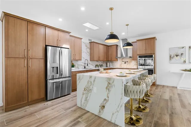 a kitchen with stainless steel appliances granite countertop a refrigerator a sink and a stove