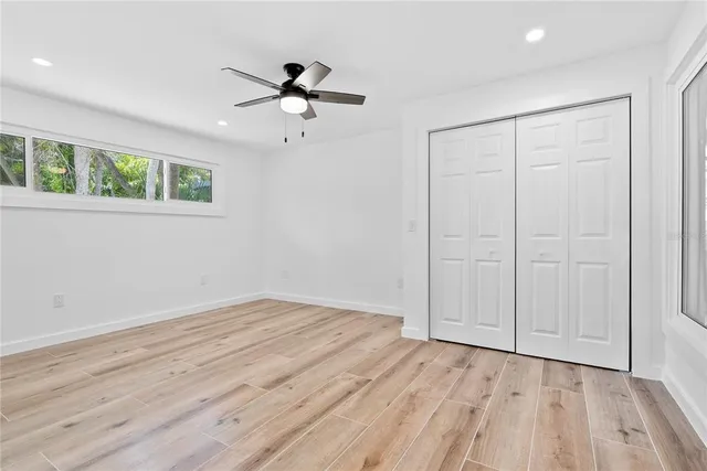 a view of empty room with wooden floor and fan