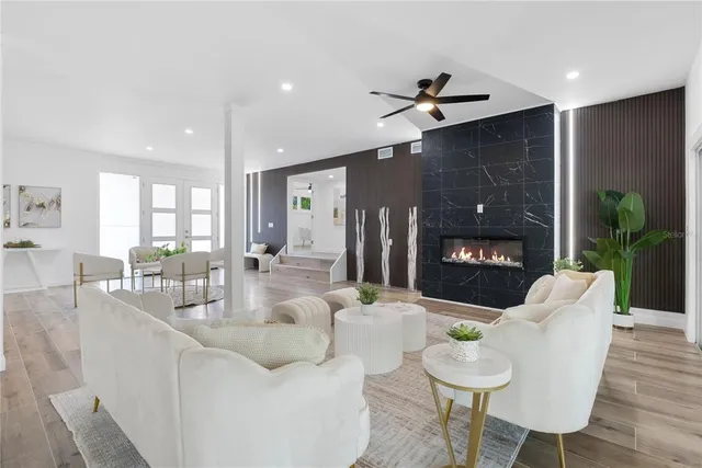 a living room with furniture a fireplace and a dining table with wooden floor