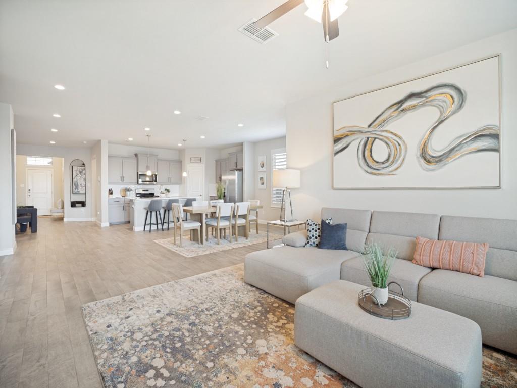 1612 Reed Drive Krum, TX 76249 - Photo 11 of 25 Open-concept living space featuring wood-finish flooring, recessed lighting, a ceiling fan, a kitchen island with seating, and stainless steel appliances