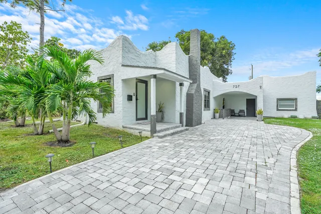 a front view of a house with a yard and potted plants