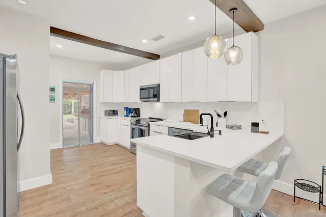 a kitchen with cabinets a sink stainless steel appliances and dining table