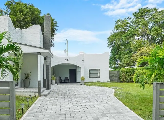 a front view of a house with a yard and potted plants