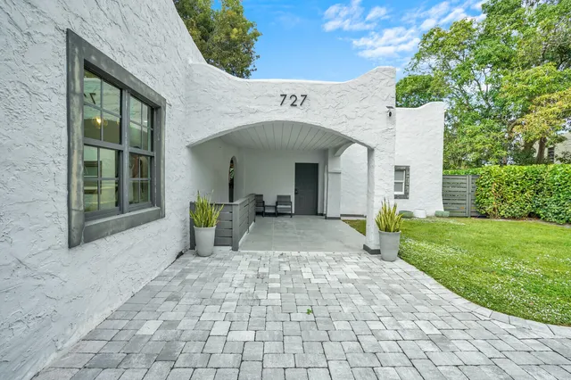 a view of a white house with a yard and large tree