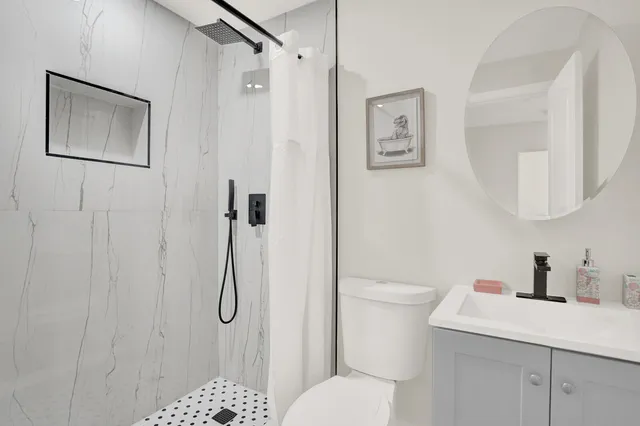 a bathroom with a toilet sink vanity and shower