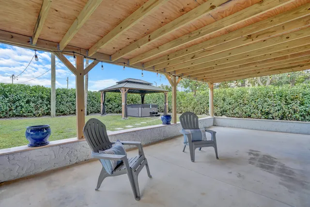 a view of a patio with table and chairs under an umbrella with a big yard