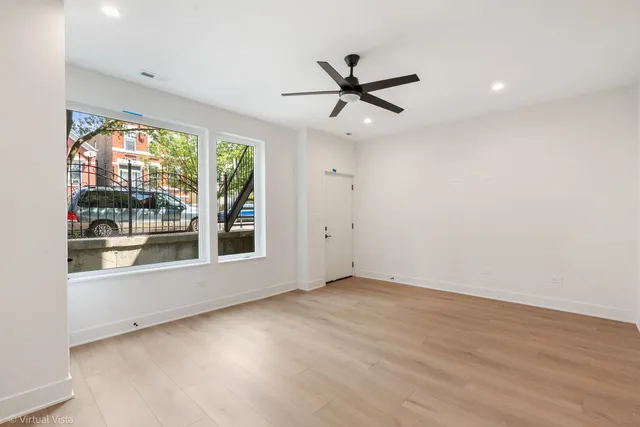an empty room with wooden floor fan and windows