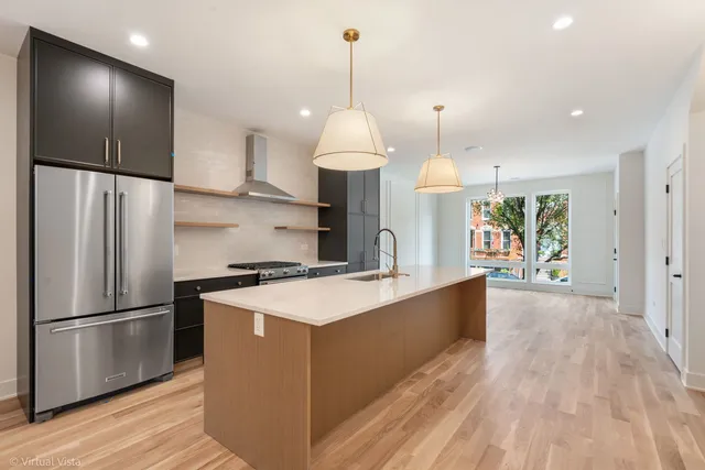 a kitchen with stainless steel appliances granite countertop a refrigerator a sink dishwasher a stove and a refrigerator with wooden floor