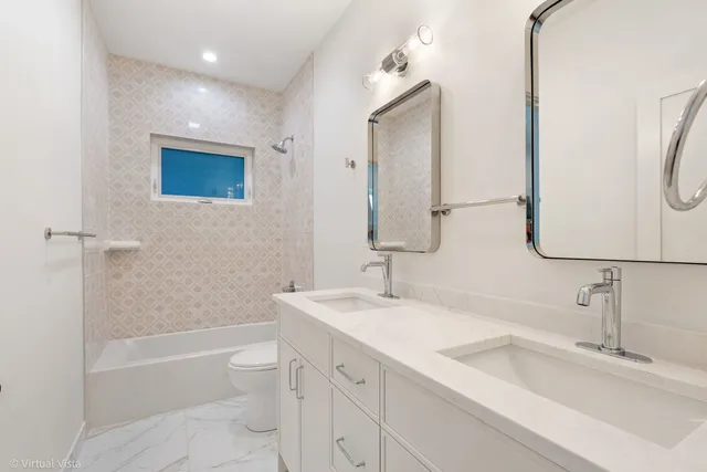 a bathroom with a double vanity sink toilet mirror and bathtub