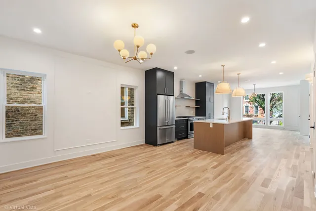 a large kitchen with stainless steel appliances a large counter top a wooden floors and a large window