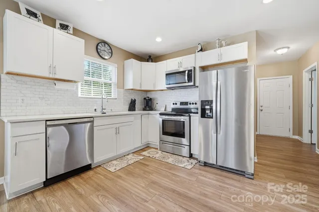 a kitchen with kitchen island white cabinets and stainless steel appliances