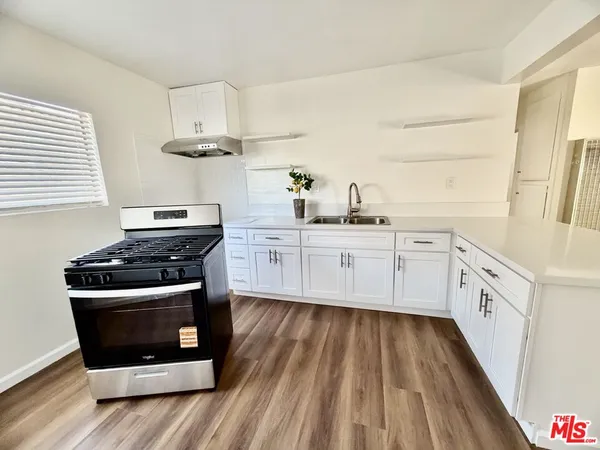 a kitchen with cabinets appliances and wooden floor
