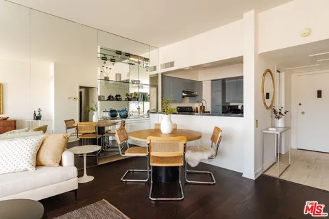 a living room with couches a coffee table and kitchen view with wooden floor