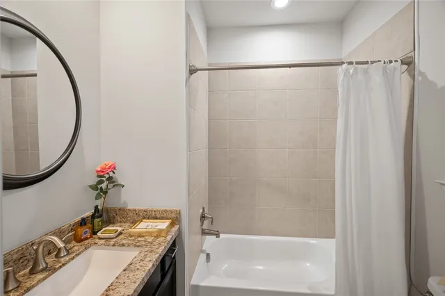 a bathroom with a granite countertop sink a mirror and a shower