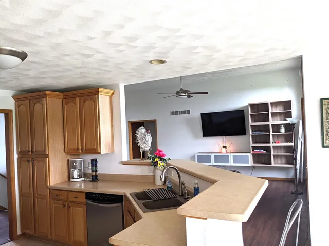 a kitchen with stainless steel appliances granite countertop a stove a sink dishwasher and microwave with wooden floor