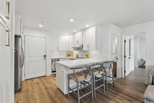 a kitchen with a table chairs refrigerator and wooden floor