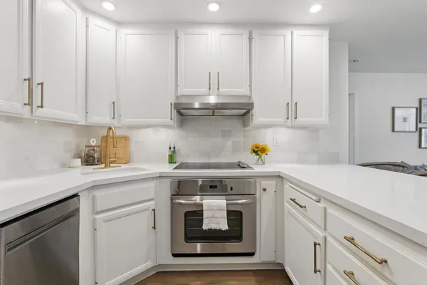 a kitchen with stainless steel appliances granite countertop a sink and cabinets with wooden floor